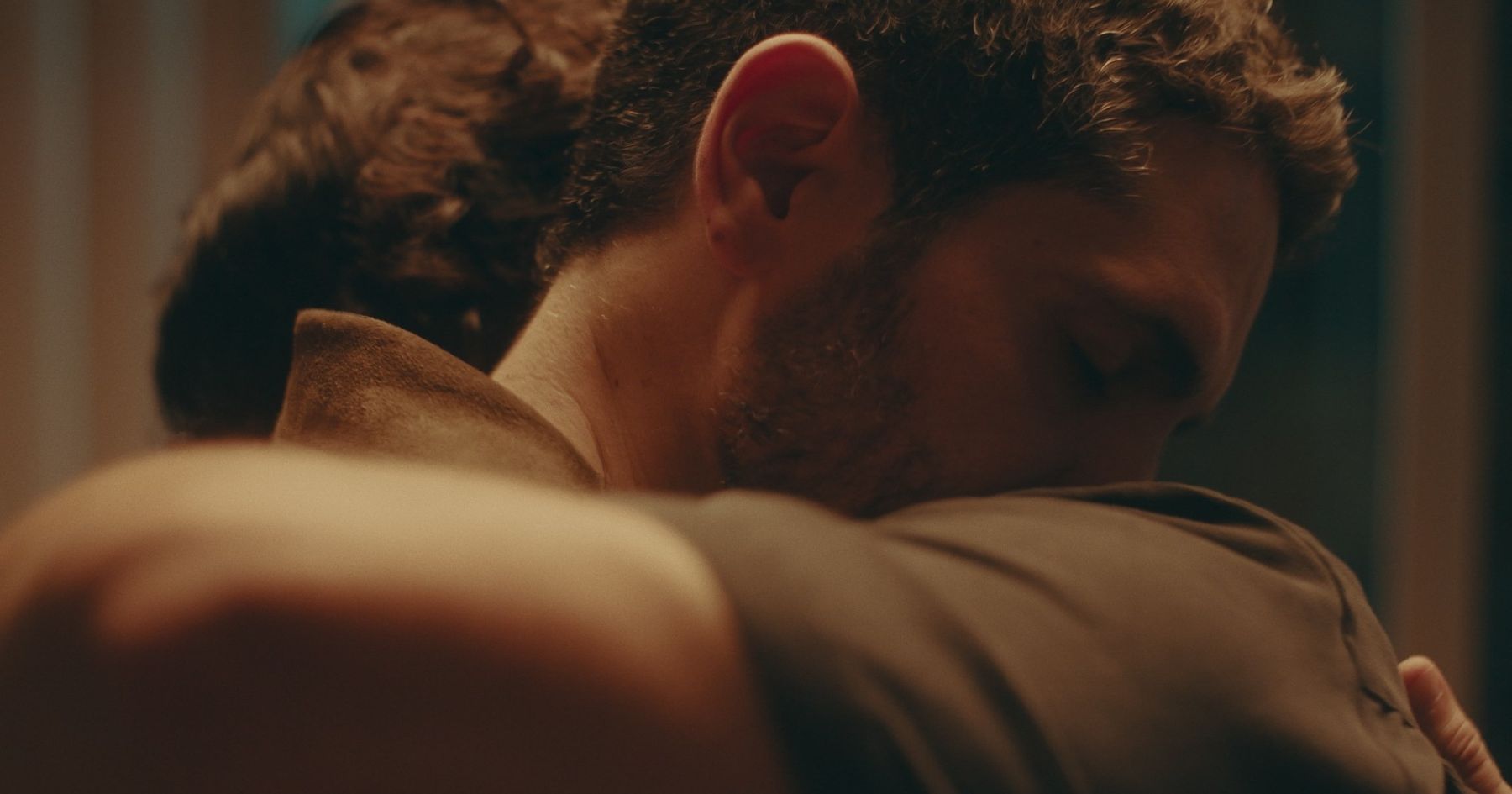Two men embracing, one's face turned into the other's shoulder